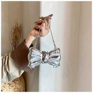 Detail of silver mirror acrylic bow handbag with elegant metal chain shoulder strap