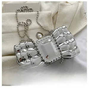 Close-up of silver bow evening bag with pearl clasp and detachable metal chain strap