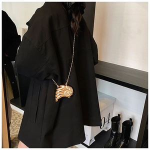 Dettaglio ravvicinato della mini borsa dorata a forma di conchiglia con trama a spirale
