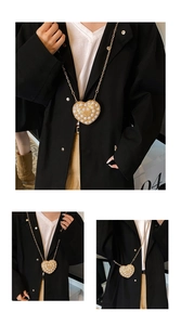 Macro view of heart-shaped mini bag with white pearls and gold chain on black blazer