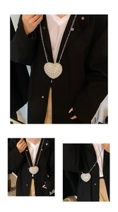 Macro detail of heart-shaped mini bag with white pearls and silver chain on black blazer