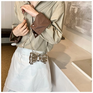 Close-up of a silver bow-shaped metallic bag with mirror finish and slim chain strap