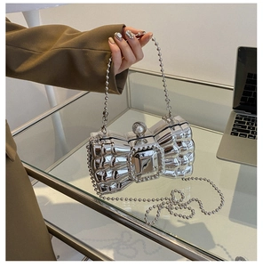 Close-up of silver bow evening bag featuring mirror finish metal and beaded chain strap