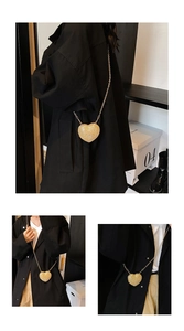 Detail of a golden heart-shaped mini crossbody bag with sparkling rhinestones and chain strap