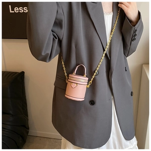 Pink mini barrel bag with lychee texture leather and golden chain on grey blazer