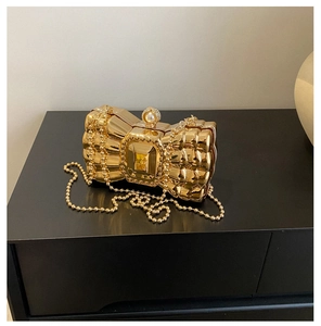 Gold bow-shaped evening clutch with central yellow gemstone and ornate pearl clasp