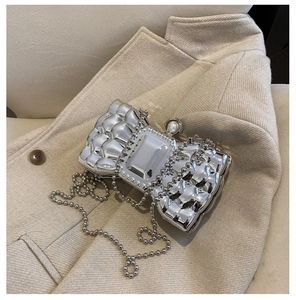 Close-up of a silver bow-shaped clutch bag with crystal detail and beaded chain link