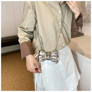 Chic silver bow-shaped acrylic evening bag with metallic chain strap on model