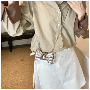 Detail of silver metallic butterfly shaped clutch with thin metal chain on a model