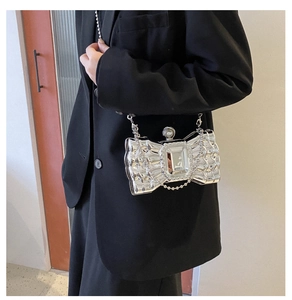 Close-up of silver bow evening bag with large crystal and fine chain strap