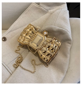 Close-up of golden bow-shaped evening clutch with pearl clasp and metallic bead chain