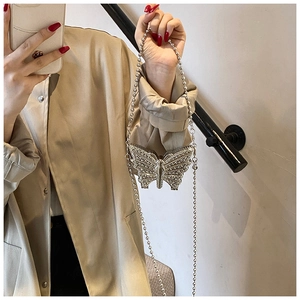 Détail d'un mini sac papillon argenté orné de strass avec une fine bandoulière chaîne