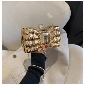 Detailed shot of golden bow evening clutch with textured metal and large crystal gem