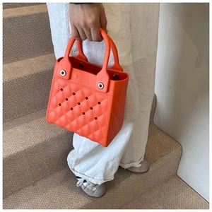 Detail der leuchtend orangefarbenen EVA-Strandtasche mit Rautenmuster und Nieten