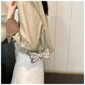 Macro view of silver bow-shaped evening bag with reflective mirror finish and chain