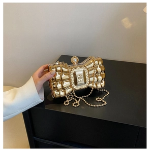 Detail of golden bow-shaped evening bag featuring pearl clasp and wavy textured metal surface