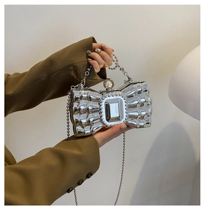 Detail of silver mirror evening clutch with butterfly bow shape and pearl clasp