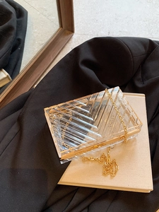 Macro shot of geometric V-shaped acrylic texture and gold metal frame on small clutch