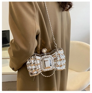 Detail of silver butterfly evening bag featuring a large gemstone and pearl clasp