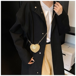 Detailed view of luxury gold heart-shaped mini bag with rhinestones on black trench coat