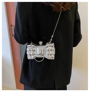 Macro view of silver metallic bow-shaped clutch showing bead detailing and top pearl clasp
