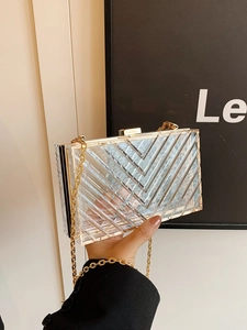 Macro detail of acrylic evening bag featuring gold metal frame and V-shaped chevron texture