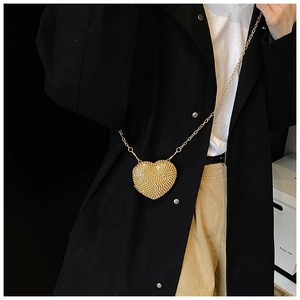 Macro shot of a heart-shaped gold evening bag with rhinestones on a crossbody chain