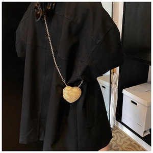 Golden heart-shaped mini crossbody bag with tassels and rhinestones on a black outfit