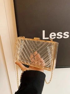 Macro shot of transparent acrylic box bag with gold metal trim and textured surface