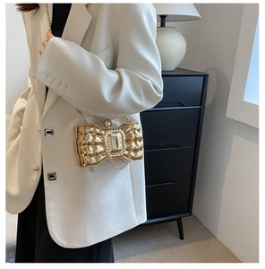 Close-up of golden bow-shaped evening clutch with pleated metal and crystal buckle