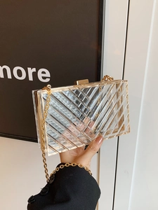 Macro shot of diagonal gold stripe pattern on clear acrylic clutch with metal chain