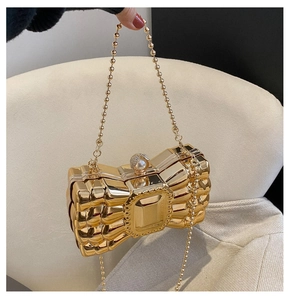 Detail of golden bow evening bag with pearl rhinestone clasp and bead chain strap