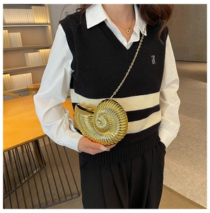 Detailed view of a gold conch-shaped metal clutch bag with spiral texture and chain strap