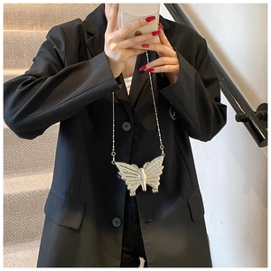 Détail du petit sac papillon argenté avec strass et chaîne sur une veste noire