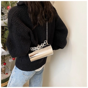 Macro view of silver cylinder clutch bag with chunky chain handle and mirror finish