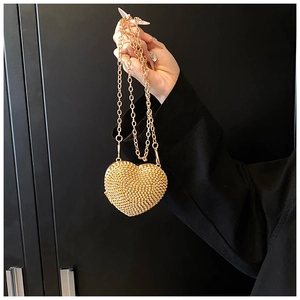 Detail of heart-shaped gold clutch featuring sparkling rhinestones and metal chain strap