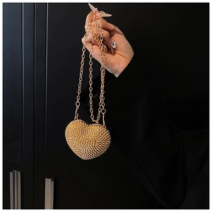 Close-up of golden heart-shaped evening clutch bag featuring sparkling rhinestones and chain