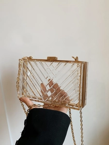 Detail of transparent acrylic clutch with geometric texture and gold chain strap