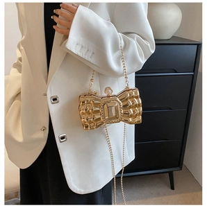 Detail of gold butterfly clutch bag with metallic grid texture and large gemstone center