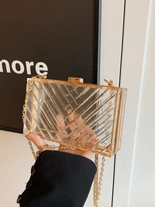 Detail of transparent acrylic clutch featuring gold metal frame and chevron pattern texture