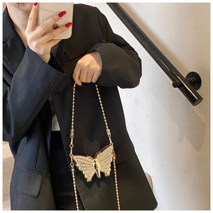 Détail du mini sac papillon doré orné de strass avec sa fine bandoulière en chaîne