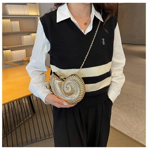 Detailed close-up of golden conch shell crossbody bag with a refined metal chain strap
