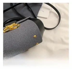 Macro shot of woven fabric bucket bag with gold Gancini style metal lock and leather trim