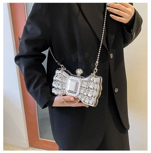 Silver bow-shaped clutch box bag with large rhinestone and pearl detail on a black blazer