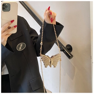 Détail du sac de soirée papillon doré avec des strass étincelants et une chaîne à billes