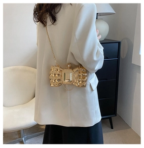 Golden butterfly clutch bag with pearl clasp and chain shown on a white blazer outfit