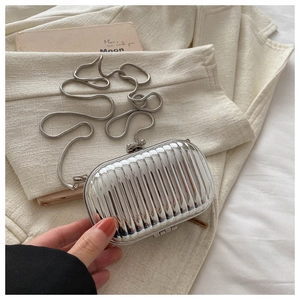Gedetailleerd overzicht van zilveren harde mini-boxtas met verticale ribbels en ketting.