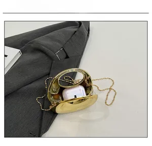 Golden oval evening clutch bag capacity demo showing interior space for wireless earbuds