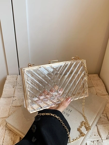 Macro detail of clear acrylic box bag with golden metal frame and V-shaped geometric texture
