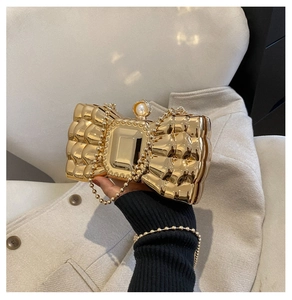 Detail of gold bow evening bag featuring pearl clasp and metallic 3D texture finish